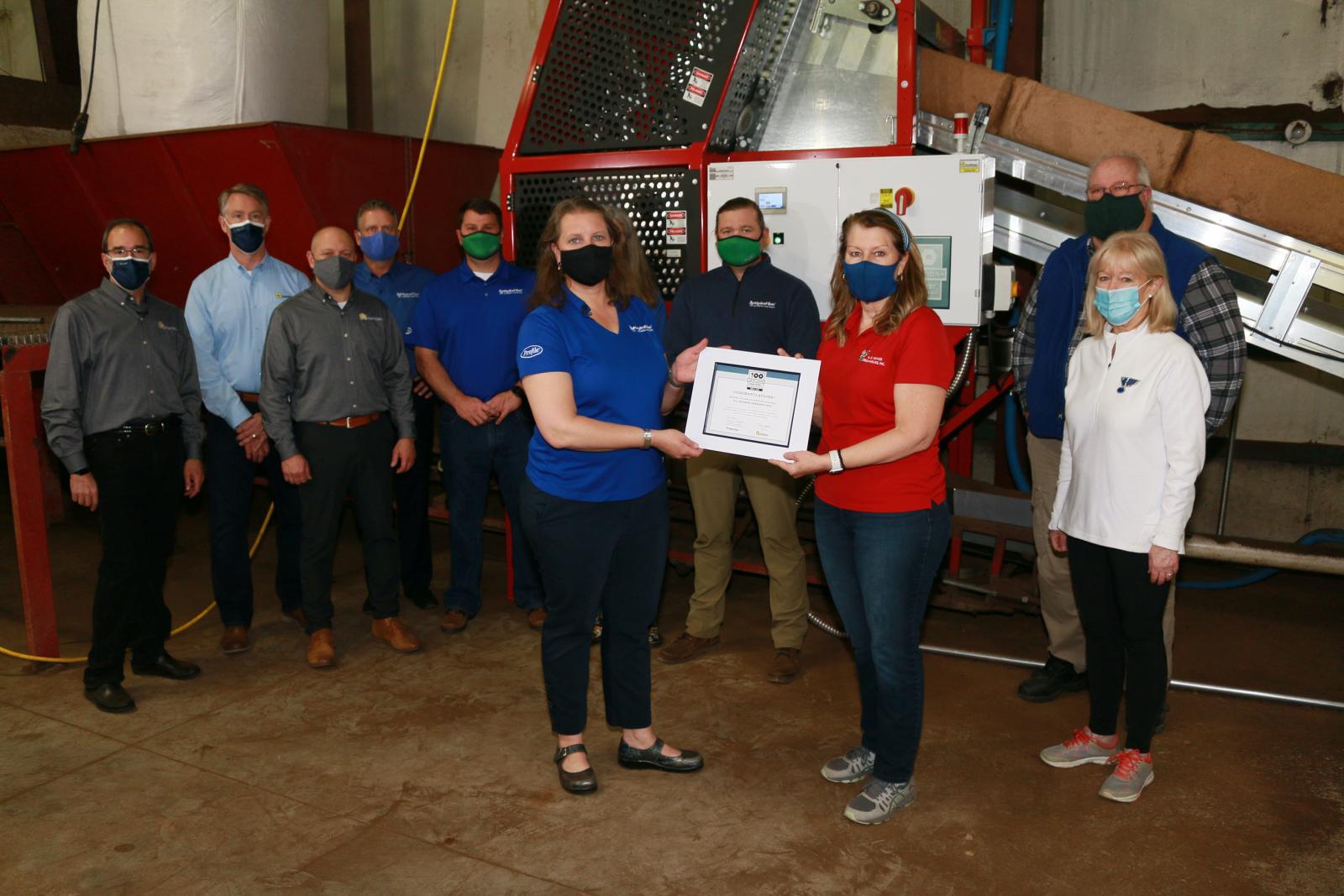 Team members from AgriNomix and HydraFiber present N.G. Heimos with a certificate for the 100th machine installation.